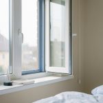 Chambre lumineuse avec de nouvelles fenêtres couvertes de condensation, une fenêtre entrouverte et un chiffon posé sur le rebord.