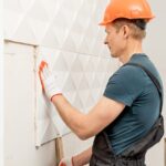 Artisan posant des panneaux muraux dans un salon contemporain.